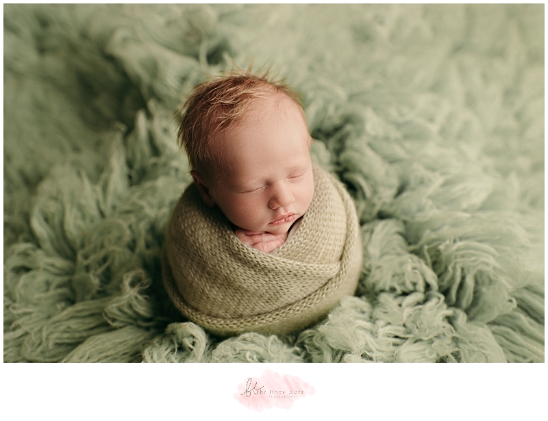 newborn baby boy wrapped on green floakti